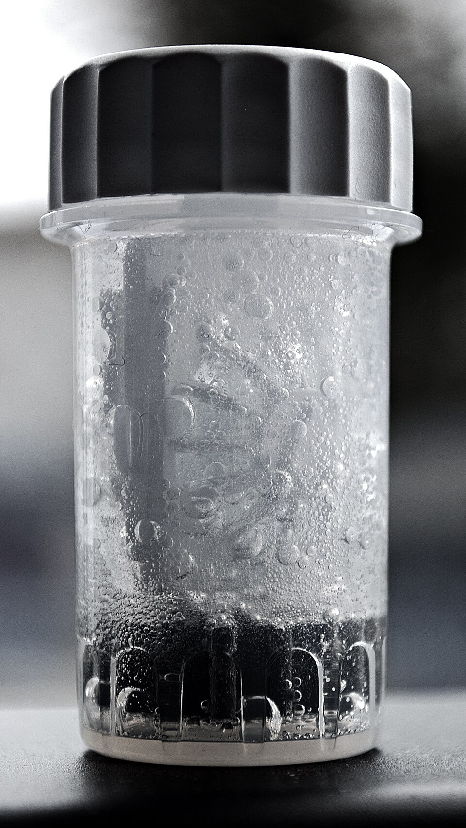 A hydrogen peroxide contact lens case with bubbles rising through the solution.